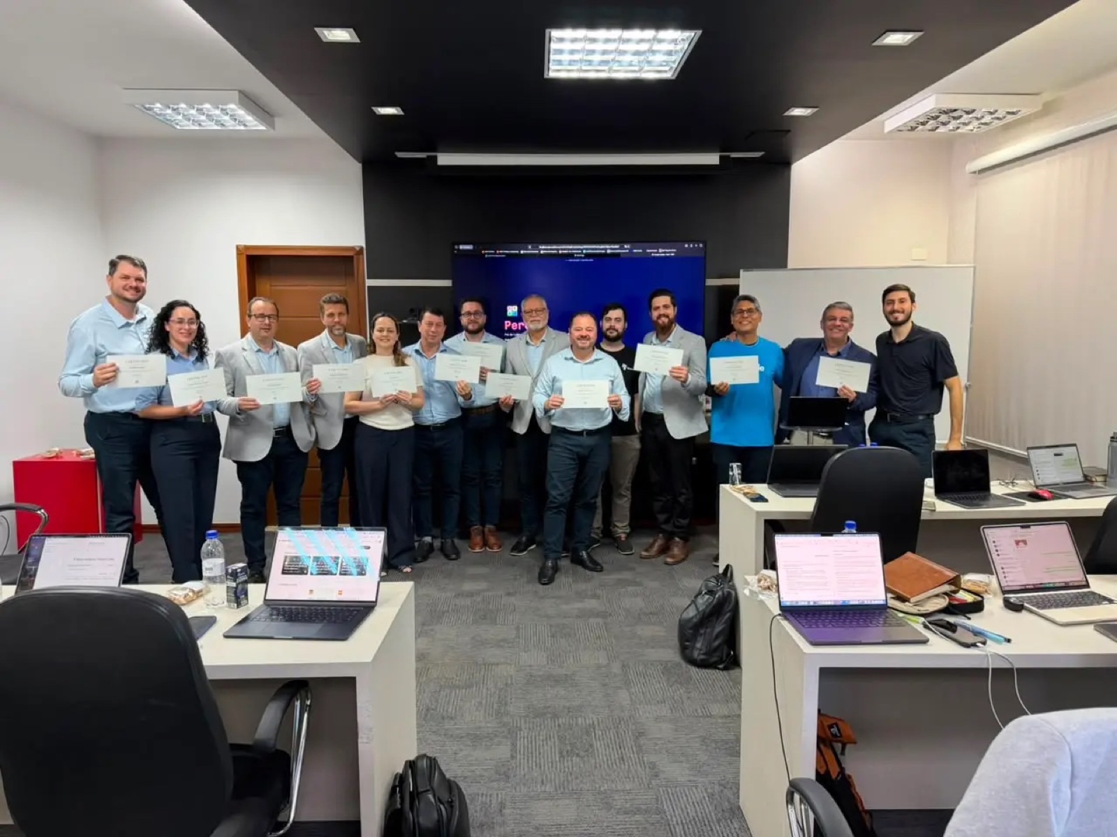 Turma e equipe da Navit reunidas após um treinamento, segurando os certificados